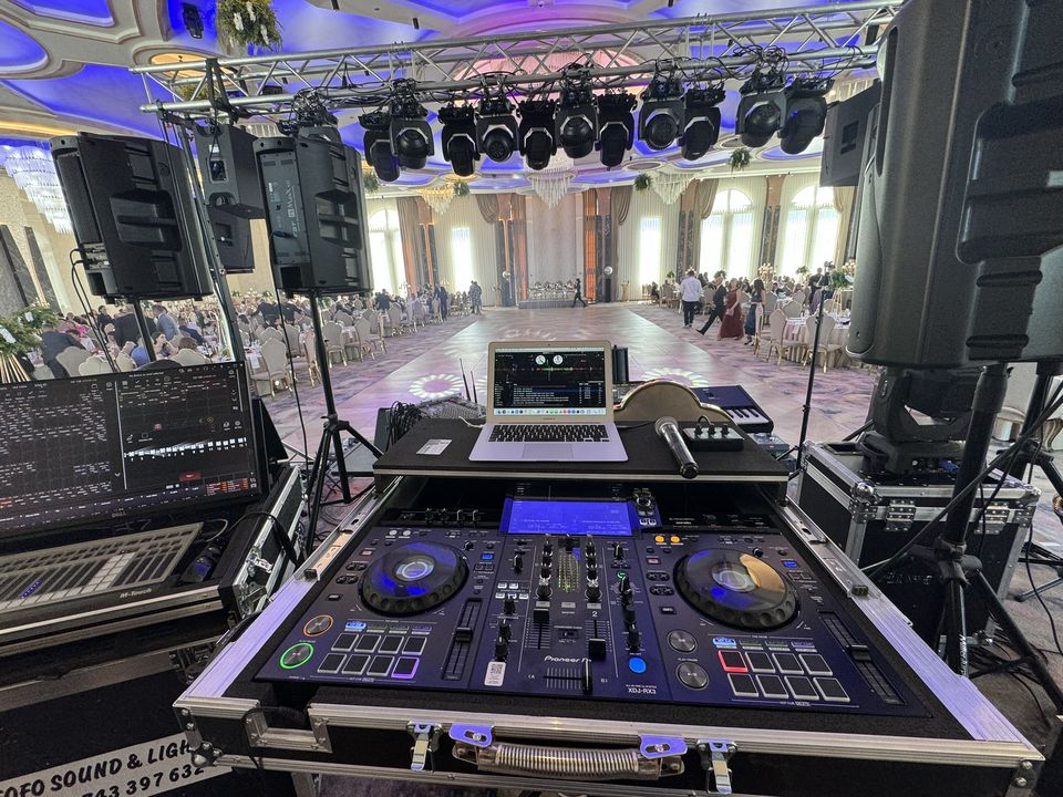 Pupitru DJ cu consolă Pioneer și laptop, boxe line array și moving head-uri într-o sală de nuntă din Sibiu