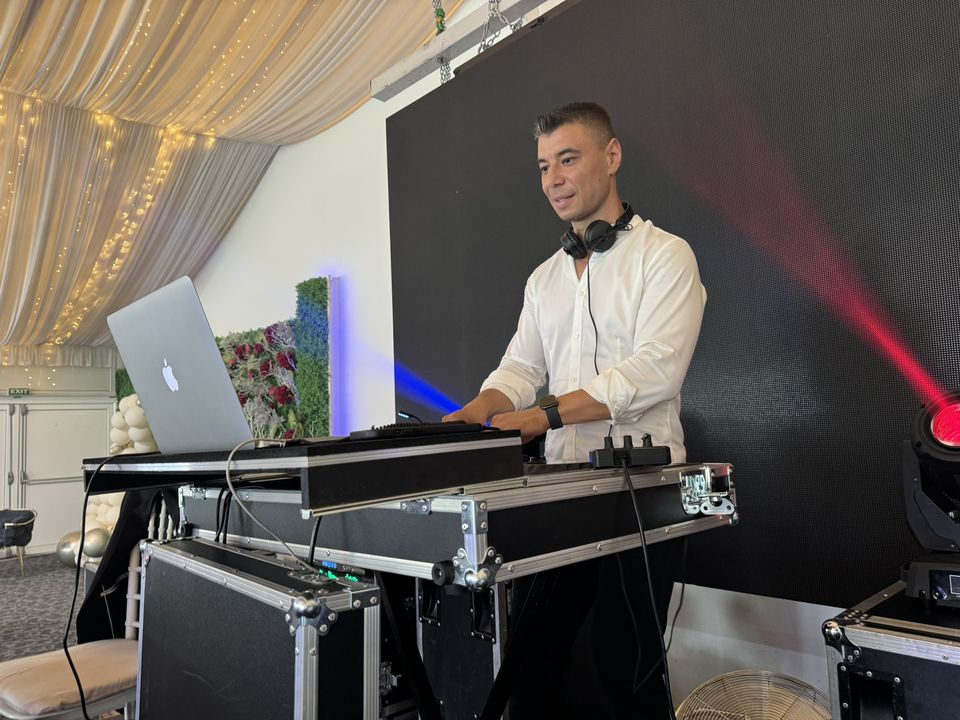 DJ profesionist mixând live la consolă, cu căști la gât și laptop, la un eveniment privat în Sibiu