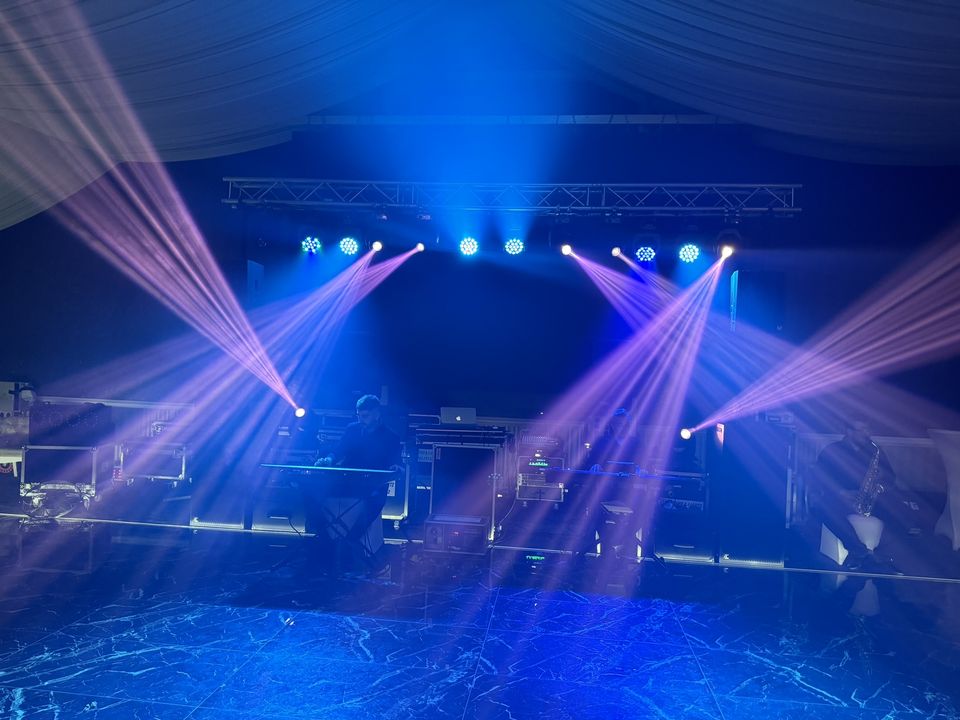 Truss cu proiectoare moving head care creează fascicule albastre și roz deasupra scenei la un eveniment în Sibiu