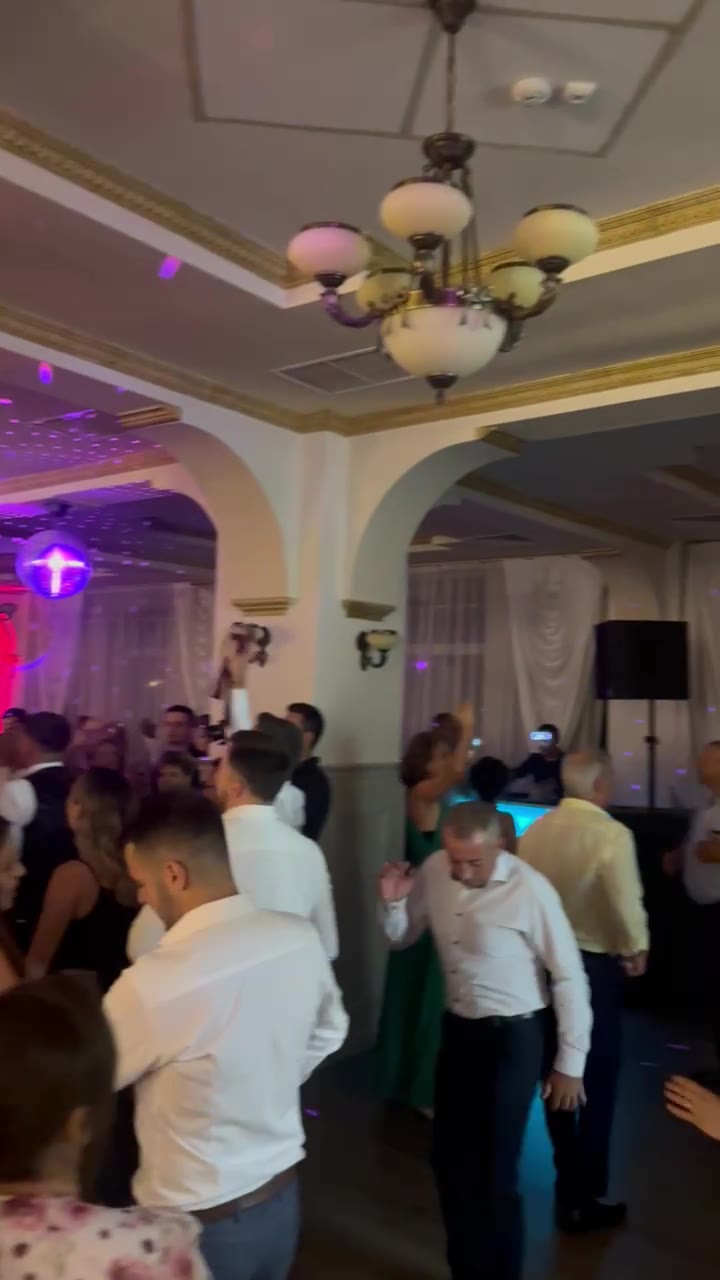 Invitați dansând într-o sală de nuntă cu candelabre și lumini colorate, Sibiu